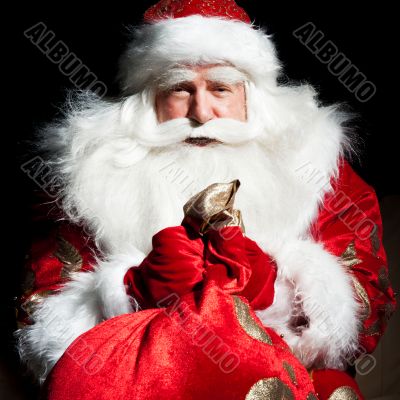 Santa sitting at the Christmas room and looking into the sack