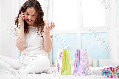Portrait of young beautiful awake woman with gifts on bed at bed