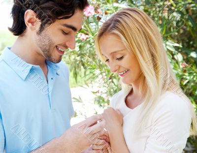 Happy young hispanic man gifting a ring to a beautiful surprised