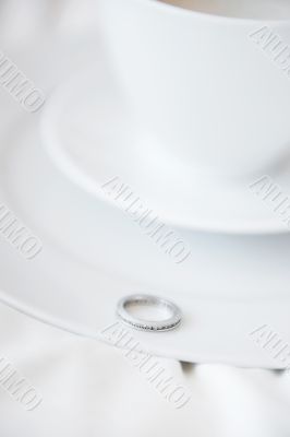 Closeup photo of proposal ring on white plate of coffee cup and 