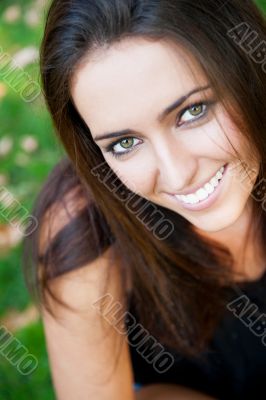 Portrait of smiling young girl sitting on grass in the forest an
