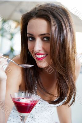 Portrait of an young beautiful woman eating an ice cream in cafe