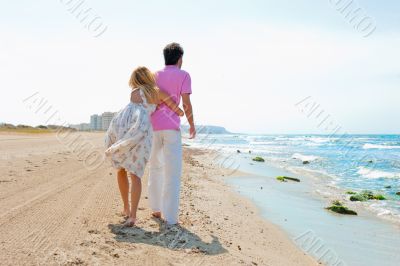 Couple at the beach holding hands and walking. Sunny day, bright