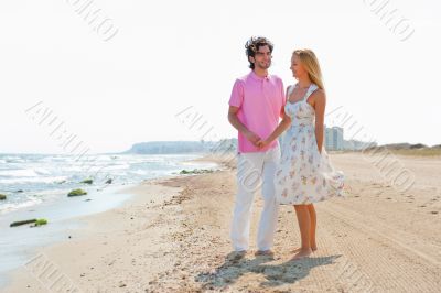 Couple at the beach holding hands and walking. Sunny day, bright