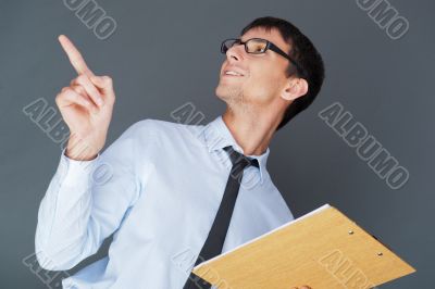 Closeup of a young smiling business man standing confidently aga