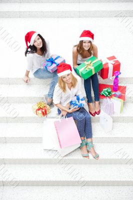 Group of three beautiful girls sitting on stairs at shopping mal
