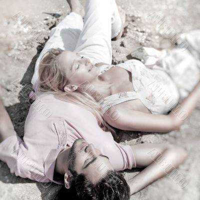 Young couple relaxing on sand at beach and daydreaming with thei