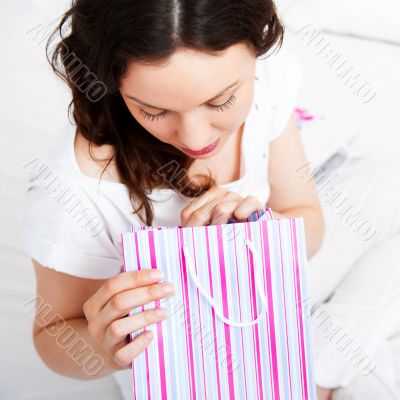 Portrait of young beautiful awake woman with gifts on bed at bed