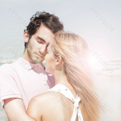 Portrait of young couple in love embracing at beach and enjoying