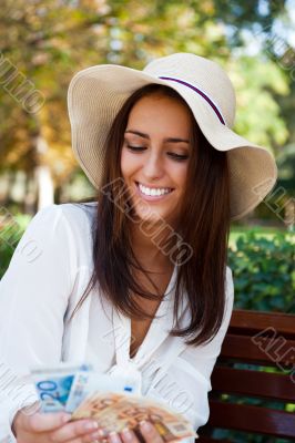 Portrait of young pretty woman sitting on bench at summer or aut