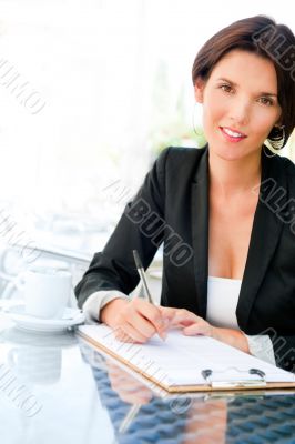 Closeup portrait of pretty woman sitting at cafe and signing doc