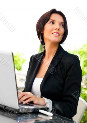 Portrait of a smiling young business woman using laptop at outdo