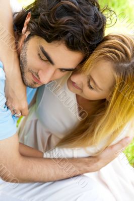 Romantic young couple sitting together in forest embracing and s