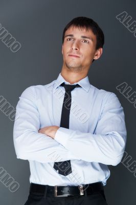 Closeup of a young smiling business man standing confidently aga