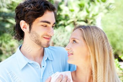 Portrait of love couple embracing outdoor in park looking happy