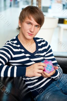 Portrait of a man with a gift box and bottle at shopping mall or