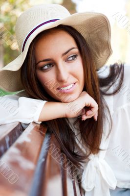 Portrait of a sexy young female smiling in a park while sitting 