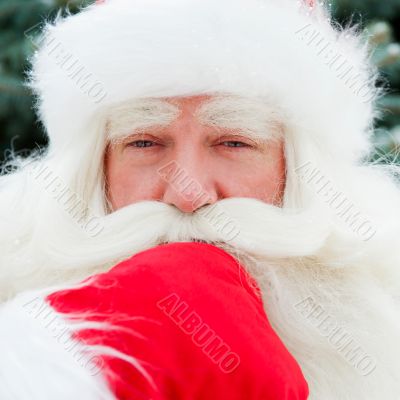 Portrait of Santa Claus standing with hand on chin outdoors at c