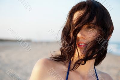 Beautiful attractive young woman standing at the beach, admiring