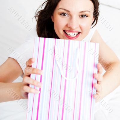 Portrait of young beautiful awake woman with gifts on bed at bed