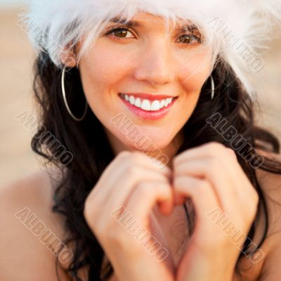 Young beautiful woman wearing christmas hat showing heart shape 
