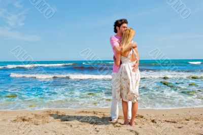 Portrait of young couple in love embracing at beach and enjoying