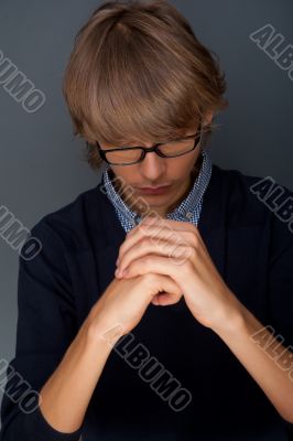 Young man praying against grey background