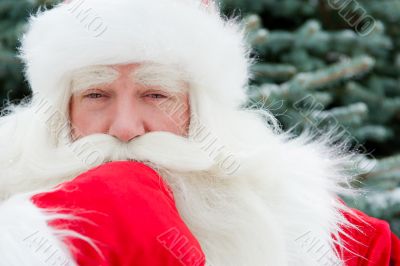 Portrait of Santa Claus standing with hand on chin outdoors at c