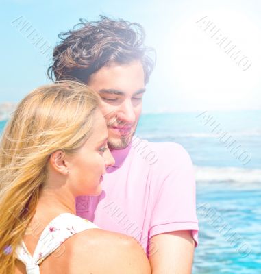 Portrait of young couple in love embracing at beach and enjoying