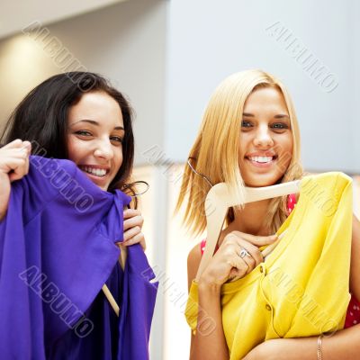 Group of two beautiful shopping women trying on clothes at shopp
