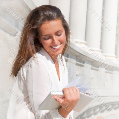 A shot of a smiling college student reading a book at park