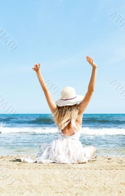 Portrait of young woman on the beach near the sea sitting with h