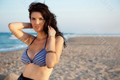 Beautiful attractive young woman at the beach standing, admiring