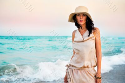 Smiling young woman wearing a straw hat and having fun at the be