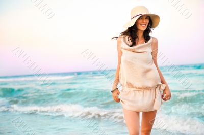 Smiling young woman wearing a straw hat and having fun at the be