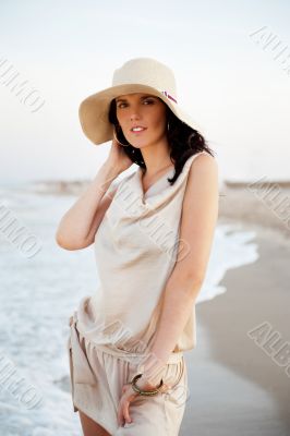 Smiling young woman wearing a straw hat and having fun at the be