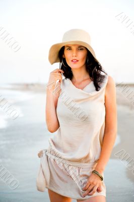Smiling young woman wearing a straw hat and having fun at the be