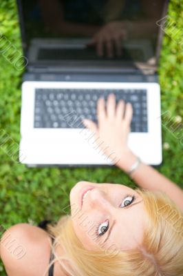 Portrait of young pretty woman resting on green grass at summer 
