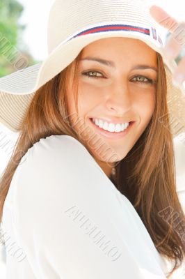 Portrait of pretty cheerful woman wearing white dress and straw 
