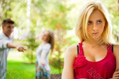 Upset teenage girl being jeered by group of the other young peop