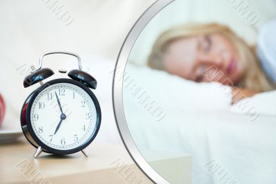 Woman sleeping in bed and alarm-clock 
