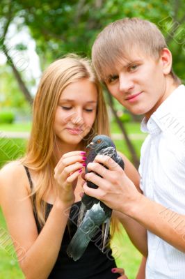Portrait of young handsome couple holding a dove in park