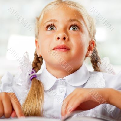 Portrait of a young girl in school at the desk.