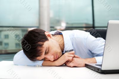 Portrait of a tired young business man sleeping on the table