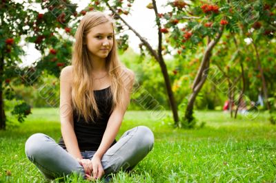 Beautiful female student outdoors sitting on grass at campus par