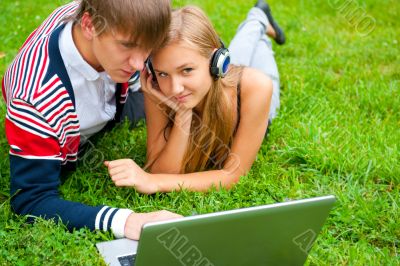 Happy young couple using laptop while lying on grass