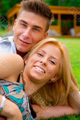 Portrait of beautiful young couple sitting on ground in park rel