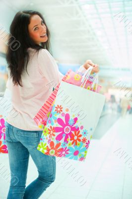 Photo of young joyful woman with shopping bags on the background