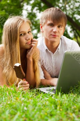 College students using laptop on campus lawn