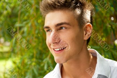 Satisfied smiling businessman standing in the green outdoors.